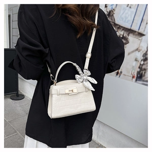 Detail of white crocodile texture handbag with silk scarf handle and metal clasp