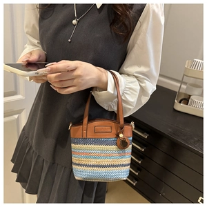 Detail of colorful woven knit bucket bag with brown leather handles and striped pattern