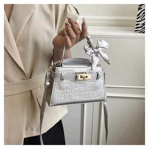 Close-up of silver crocodile embossed handbag with decorative silk scarf on the top handle