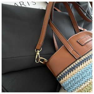 Close-up of contrast woven straw bucket bag with leather strap and golden hardware