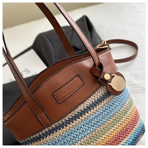 Close-up of rainbow woven beach tote showing brown leather handles and gold charm