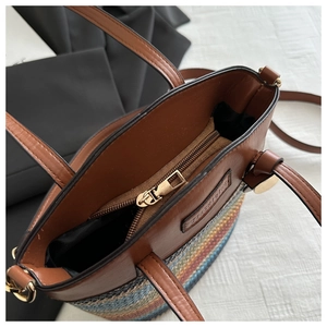 Detail of colorful woven straw tote with brown leather handles and gold metal zipper