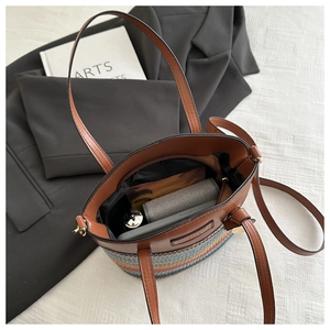Detail view of woven straw bucket bag with brown leather trim and colorful base design