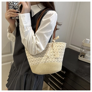 Detail of crochet lace tote bag featuring beige floral pattern and straw base