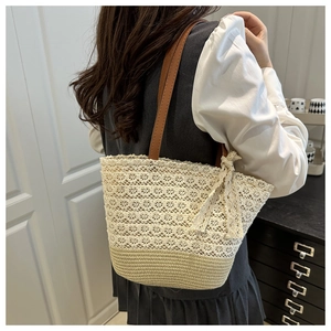 Detail of beige lace woven tote bag with brown leather handles and side bow accent