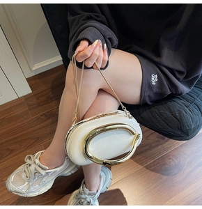 Detail of white leather handbag with large gold U-shaped metal handle and chain