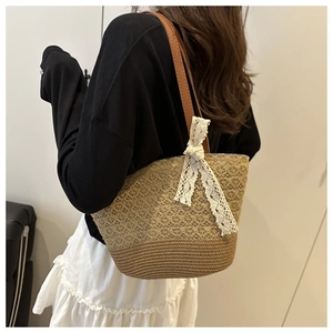 Detail of woven straw tote bag featuring intricate crochet patterns and a lace bow accent