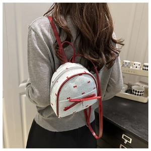 Vista posteriore di una modella con il mini zaino bianco a pois e un fiocco rosso