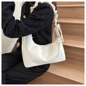 Detail of white half-moon underarm bag with pleated strap texture and soft leather finish