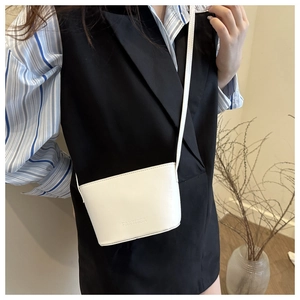 Close-up of white minimalist mini bucket bag with embossed logo on a female model