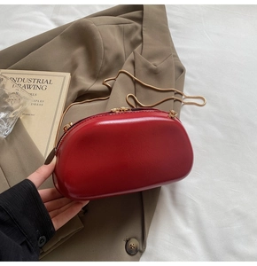 Detail of red patent leather mini evening bag with gold chain strap and metal handle