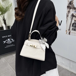White crocodile pattern top handle bag with silk scarf and gold twist lock in urban setting