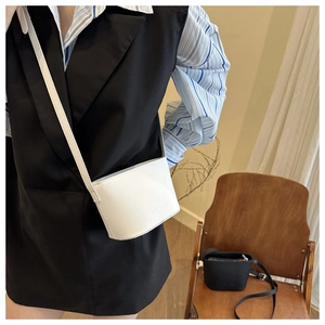 Mini crossbody bucket bags in white and black leather with pebble texture and slim strap