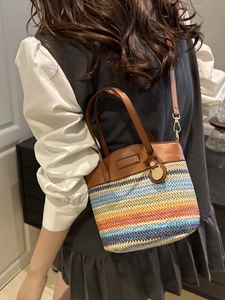Colorful striped woven bucket bag with brown leather handles and adjustable shoulder strap