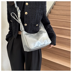 Detailed shot of silver metallic crescent bag with scrunchie strap and bow decoration