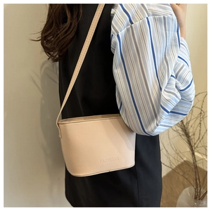 Minimalist beige crossbody bucket bag with FANYISSA letter embossing on matte faux leather