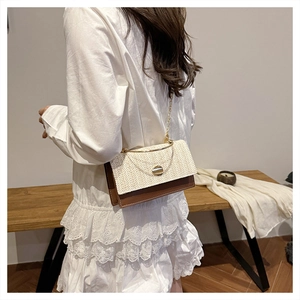 Detail of woven straw crossbody bag with brown leather flap and gold metal handle