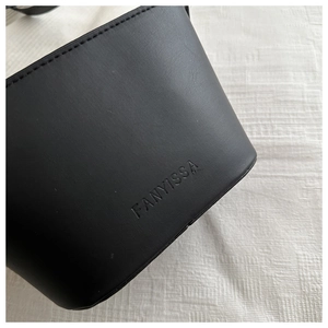 Close-up of matte black leather bucket bag featuring FANYISSA embossed brand logo and stitching