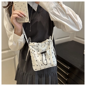 Macro view of white quilted crossbody bag with black butterfly embroidery and drawstring