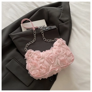 Détail du sac baguette rose avec roses en tissu 3D et bandoulière en chaîne