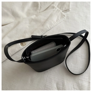 Detail view of small black leather bucket bag showing internal storage capacity and strap