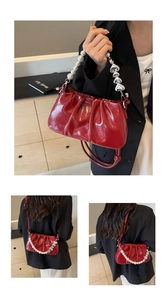 Detail of red pleated patent leather cloud bag with pearl and heart metal strap