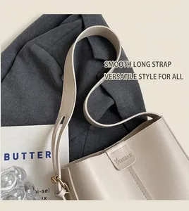 Detail of off-white bucket bag with embossed logo and adjustable long shoulder strap
