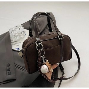 Détail du sac bowling en daim marron foncé avec breloques baseball et bandoulière