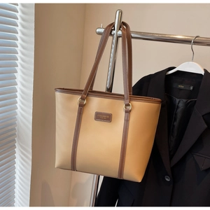 Detail of light brown tote bag with metal rings hanging next to a black blazer