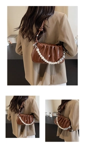 Detail of brown pleated cloud bag with pearl chain and silver heart ring accents