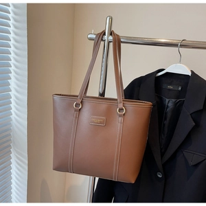 Detailed view of brown lychee texture leather tote bag with white contrast stitching