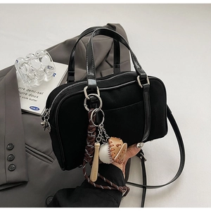 Vue détaillée du sac bowling noir rétro avec poignées en cuir et breloques de baseball