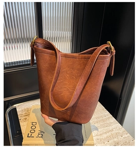 Detail of vintage brown bucket bag with smooth oil-wax texture and adjustable strap