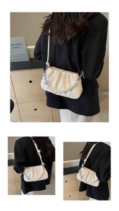 Close-up of white glossy pleated cloud bag with pearl heart chain and silver hardware