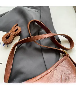 Detailed macro view of vintage brown leather texture and dual straps on crossbody bag
