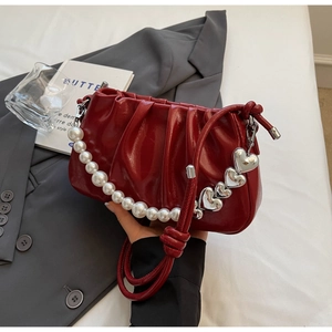 Close-up of wine red patent leather pleated bag with pearl chain and heart charms