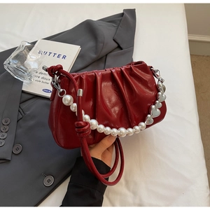 Detail of red pleated leather bag with pearl heart chain and slim shoulder strap