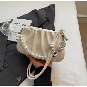 Detailed shot of a white pleated cloud bag with pearl handle and silver heart charm