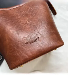 Close-up of dark brown vintage bucket bag featuring embossed brand logo and metal feet