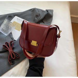 Flat lay of wine red vintage handbag with gold buckle and adjustable strap