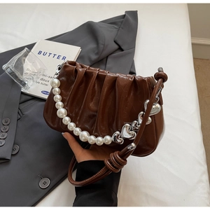 Detailed view of dark brown pleated cloud bag with pearl and silver heart chain