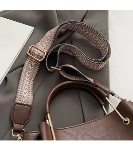 Detail of coffee brown bucket bag with adjustable geometric pattern woven shoulder strap