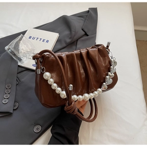 Detailed shot of brown pleated cloud bag with pearl chain and silver heart pendant
