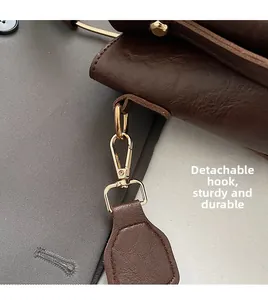 Macro detail of golden detachable clasp and brown lychee grain leather on a bucket bag