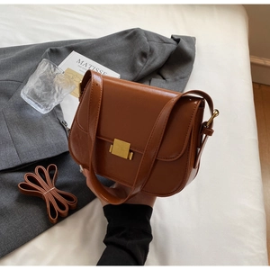 Detail of vintage brown saddle bag featuring polished gold buckle and adjustable strap