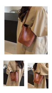 Close-up of the vintage brown leather bucket bag with embossed logo and adjustable strap