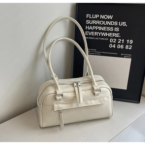Detail of cream white pillow bag with dual zippers and long leather tassel accents