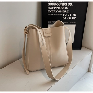 Close-up of beige leather bucket bag featuring a gold metal buckle and embossed brand logo
