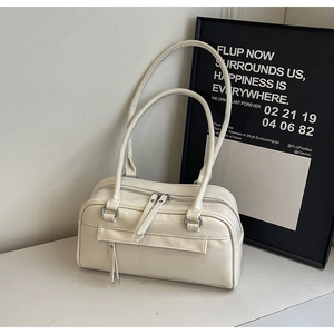 Detail of cream white faux leather bag featuring smooth texture and long strap handles