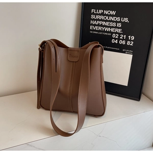 Detail of a brown leather bucket bag showing vertical stitching and embossed logo design